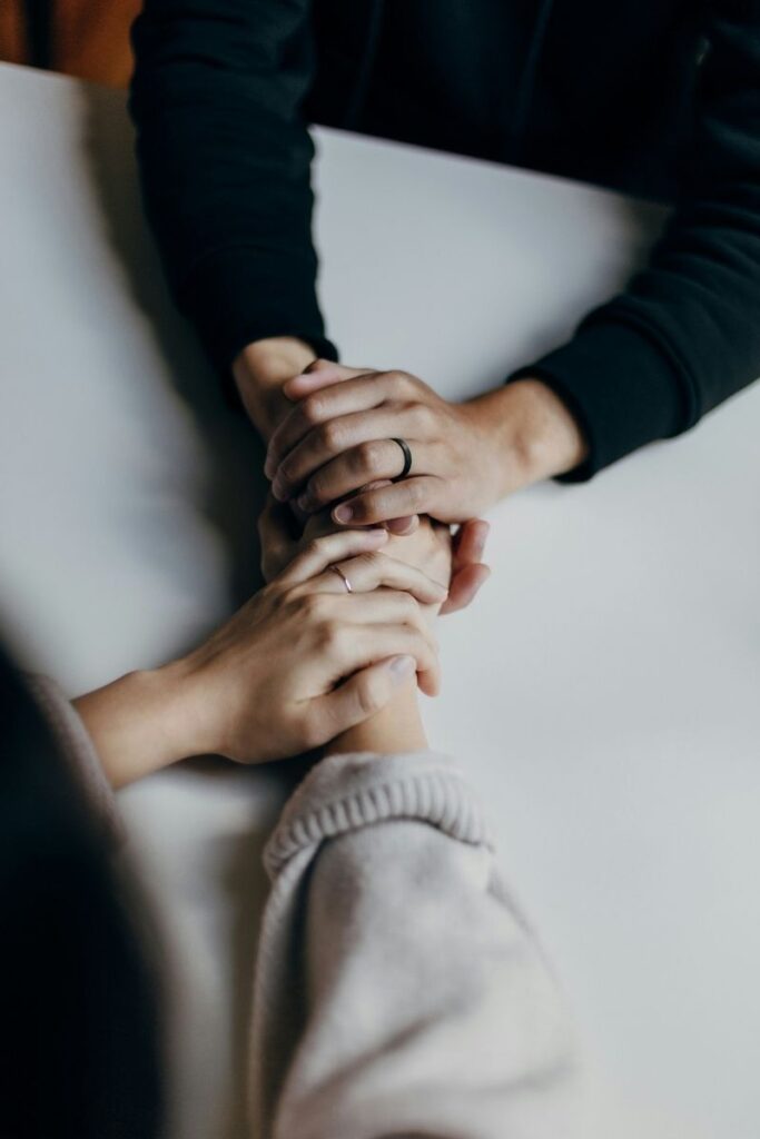 Deux paires de mains se tenant avec bienveillance, dans un geste de soutien et d'écoute